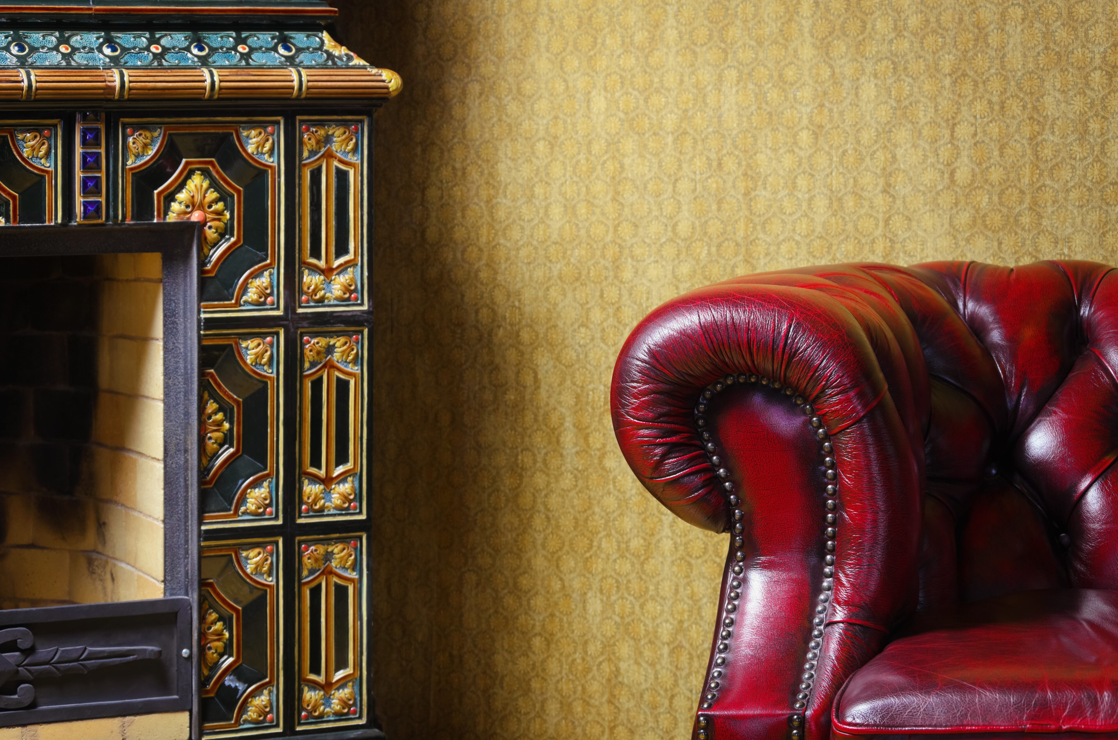 Red leather armchair beside an antique fireplace